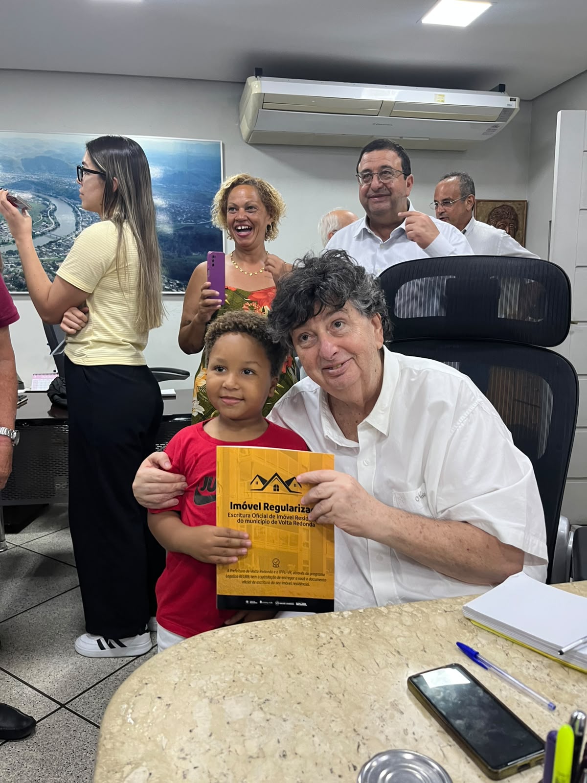 Prefeito de Volta Redonda entregando a escritura de imóvel regularizado ao beneficiário